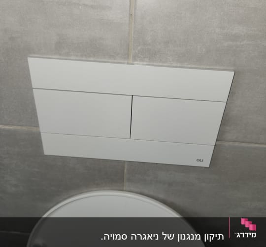 לחצן הדחה כפול על קיר אריחים אפור